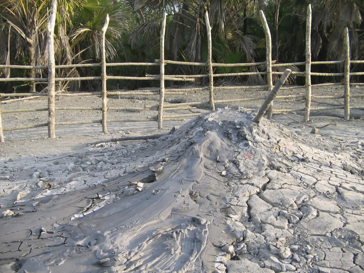 Small mud volcano cone behind a wooden fence at Baratang