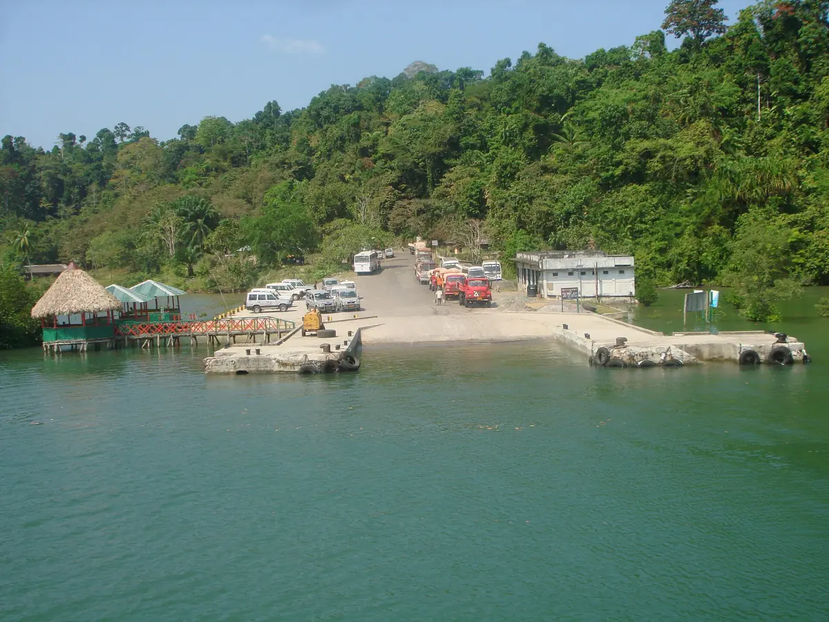 Ferry jetty at the Middle Strait with cars waiting beside green forest