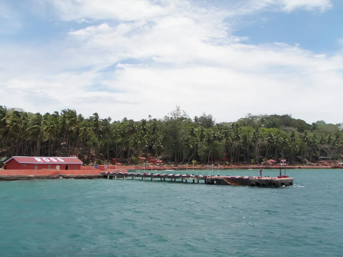 Ross Island coast with a pier and coconut palms seen from the water